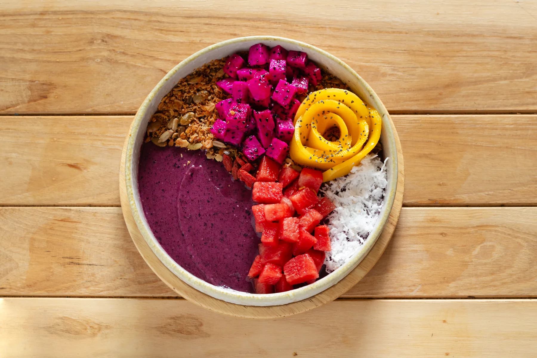A fruit and granola bowl on a wooden table