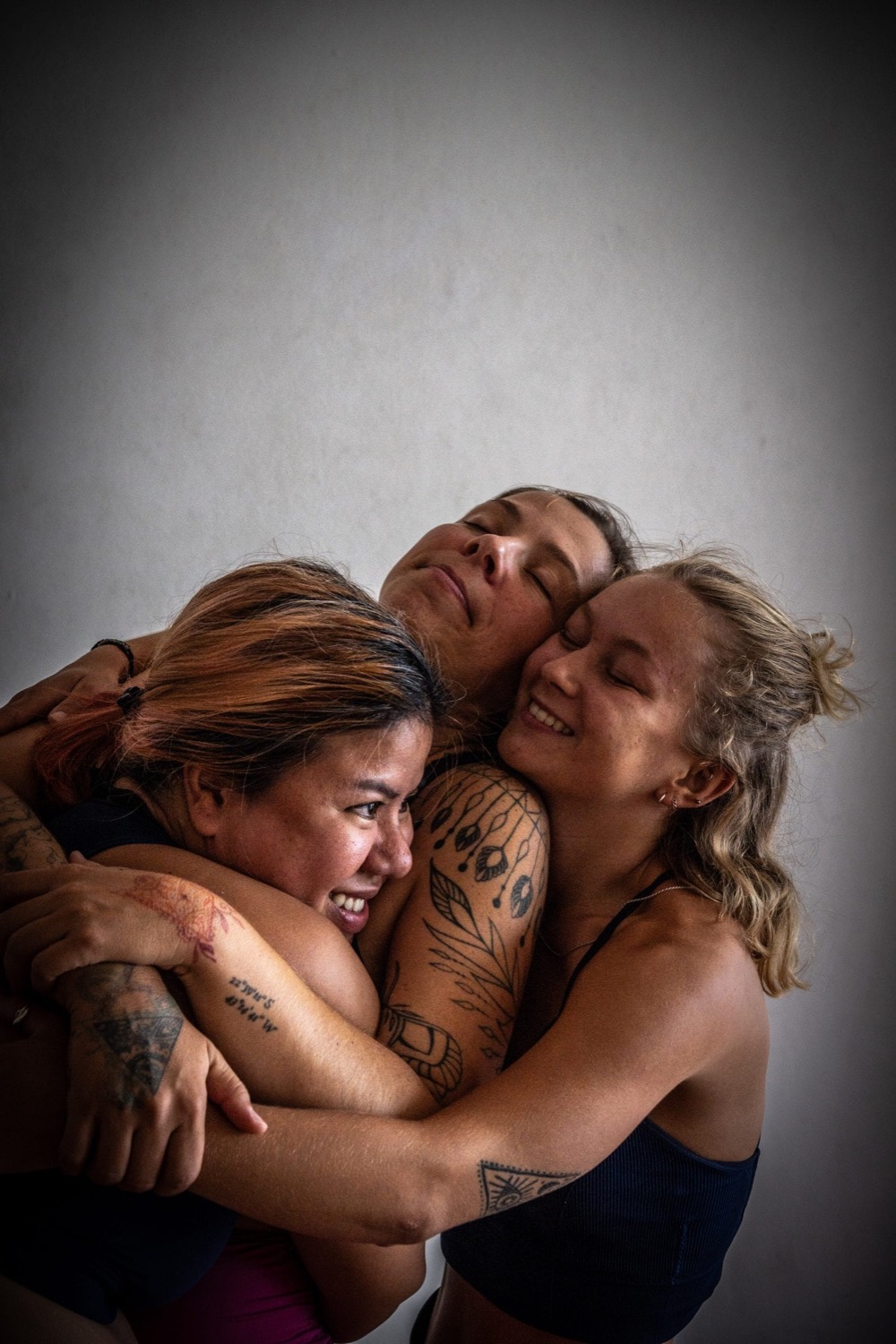 Three friends embracing after practice at Blue Chitta