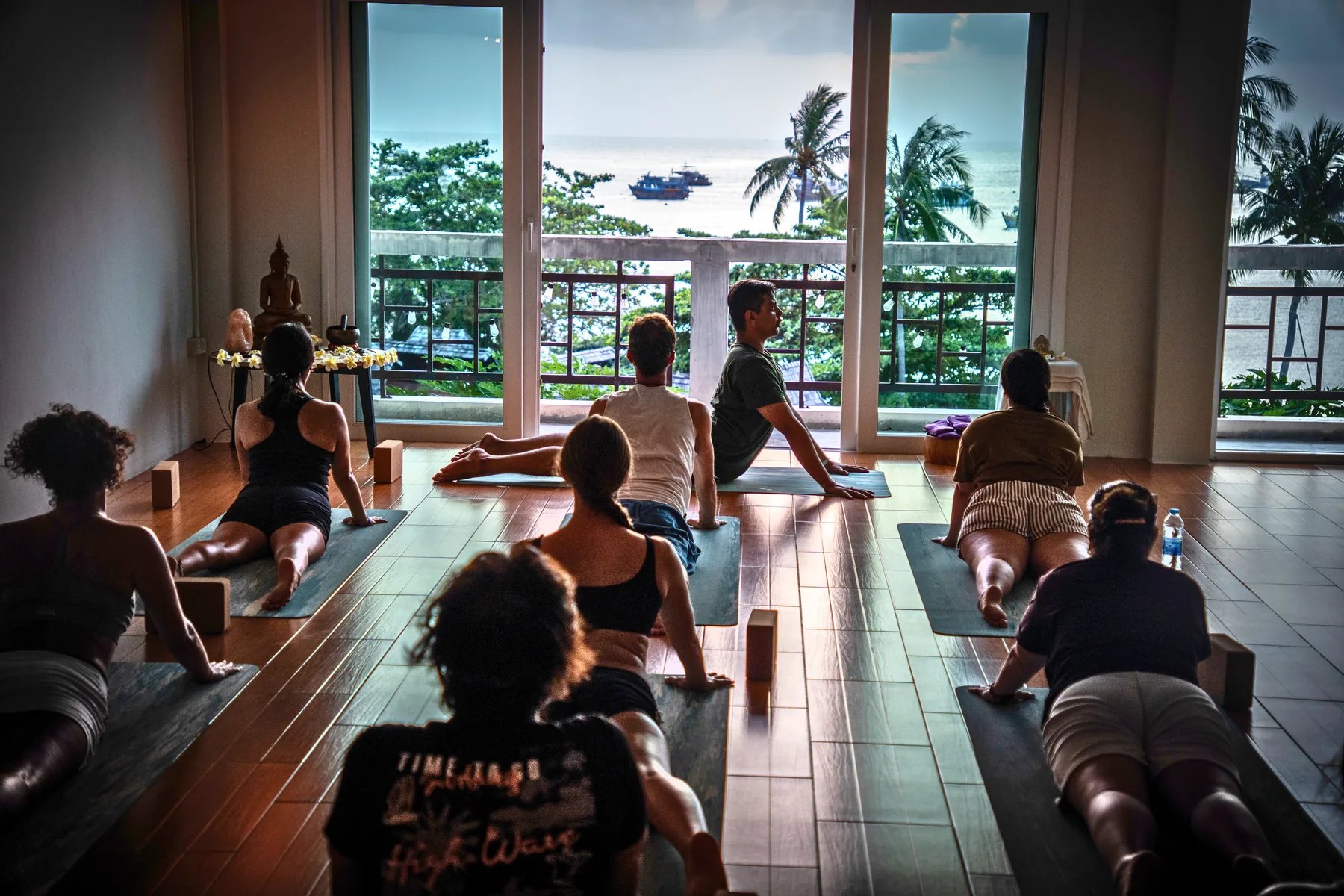 A class sitting in the shala with the sea through the open doors